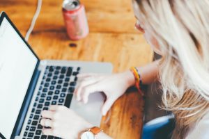 Woman typing on a laptop at a wooden table