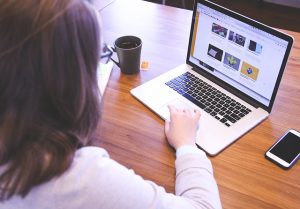 Woman working at a laptop with a coffee cup and phone on a wooden desk