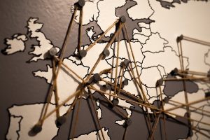 World map with pins and string connecting locations across Europe