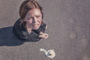 Woman looking up in dismay at a dropped ice cream on the pavement