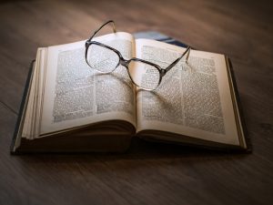 Open book with a pair of reading glasses resting on it