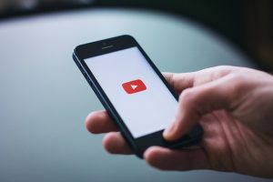 Hand holding a phone displaying the YouTube app