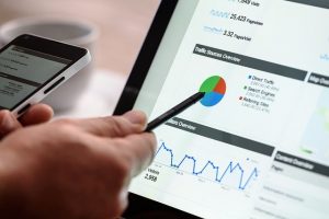 Hand using a stylus on a tablet showing website analytics charts