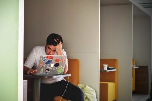 Man sitting at a laptop resting his head in his hand