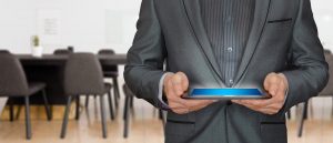 Man in a suit holding a tablet in a meeting room