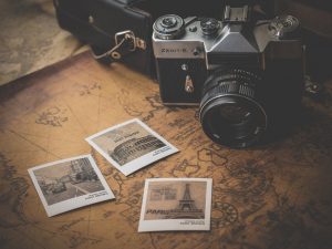 Vintage film camera beside printed photographs on an old map