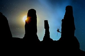 Climber silhouetted against a night sky beside desert rock formations