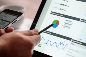 Hand using a stylus on a tablet showing website analytics charts