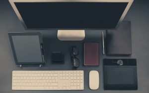 Overhead view of a tidy desk with a monitor, tablet, keyboard and notebook