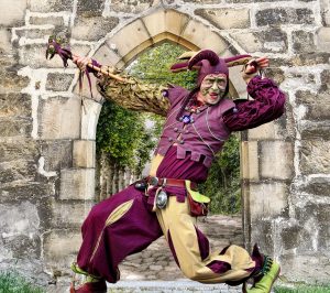 Performer dressed as a jester posing in a stone archway