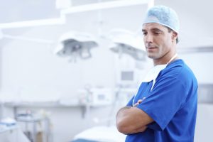 Surgeon in scrubs standing with arms folded in an operating theatre