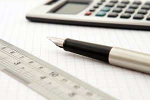 Calculator, pen and ruler resting on a sheet of graph paper