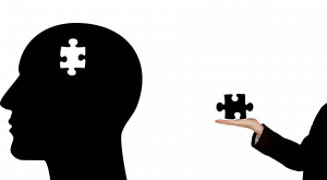 Silhouette of a head with a jigsaw piece missing and a hand offering the piece