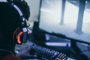 Gaming headset resting beside a backlit keyboard and monitor