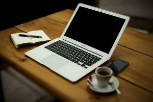 Laptop, notebook and an espresso cup on a wooden desk