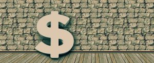 Large wooden dollar sign standing against a stone wall